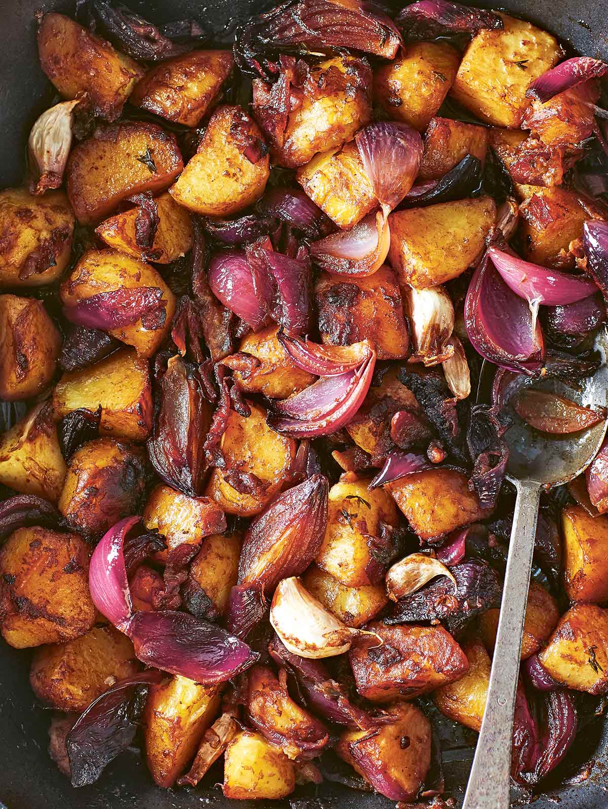 A roasting pan filled with balsamic roasted potatoes and red onions and garlic