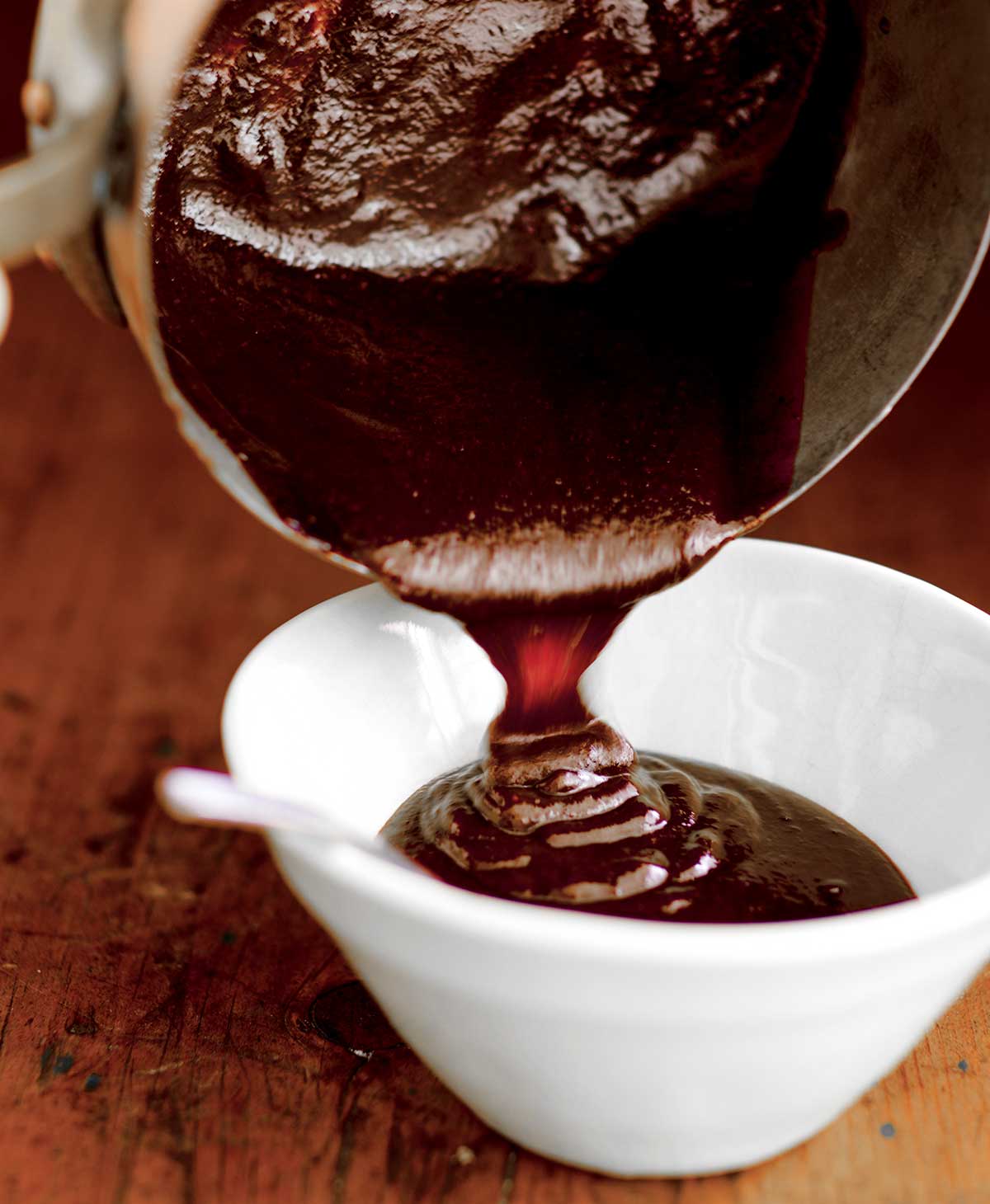 Bobby Flay's barbecue sauce being poured from a pot into a white bowl.