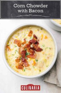 A bowl of corn chowder with bacon sprinkled on top.