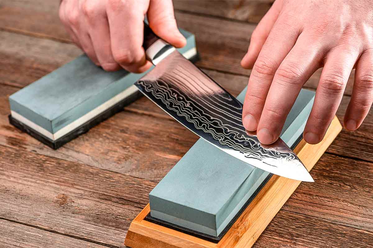 A person sharpening a knife on a whetstone.