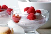 Two parfait-style serving dishes filled with raspberry fool, and topped with fresh raspberries.