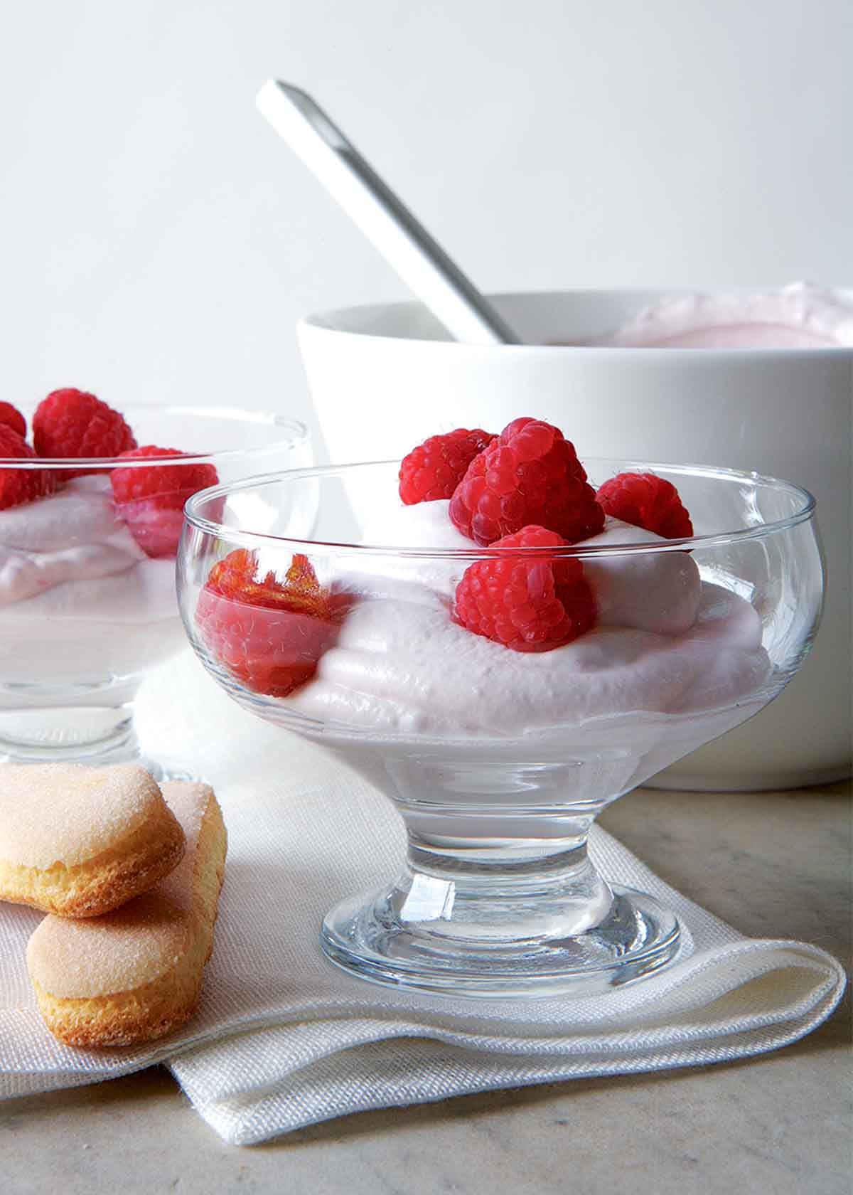Two parfait-style serving dishes filled with raspberry fool, and topped with fresh raspberries.