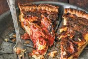A metal pie plate with two slices of roasted tomato quiche, some crumbs of crust and a fork.