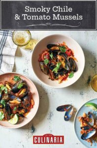 Three bowls of smoky chile and tomato mussels, on a table flanked by a glass of beer and a few empty mussel shells.