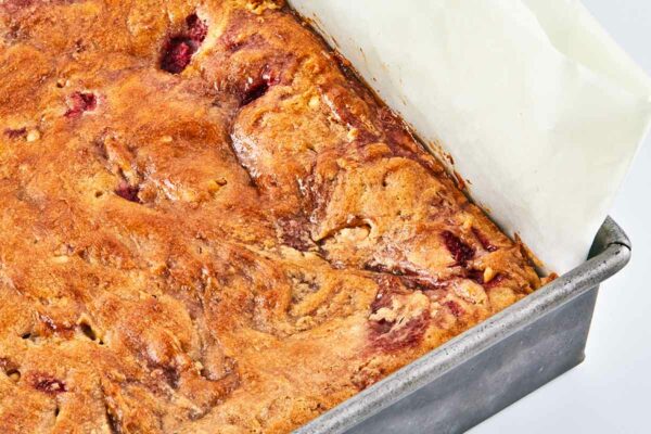 A metal pan filled with a parchment sling and peanut butter and jam swirled blondies.