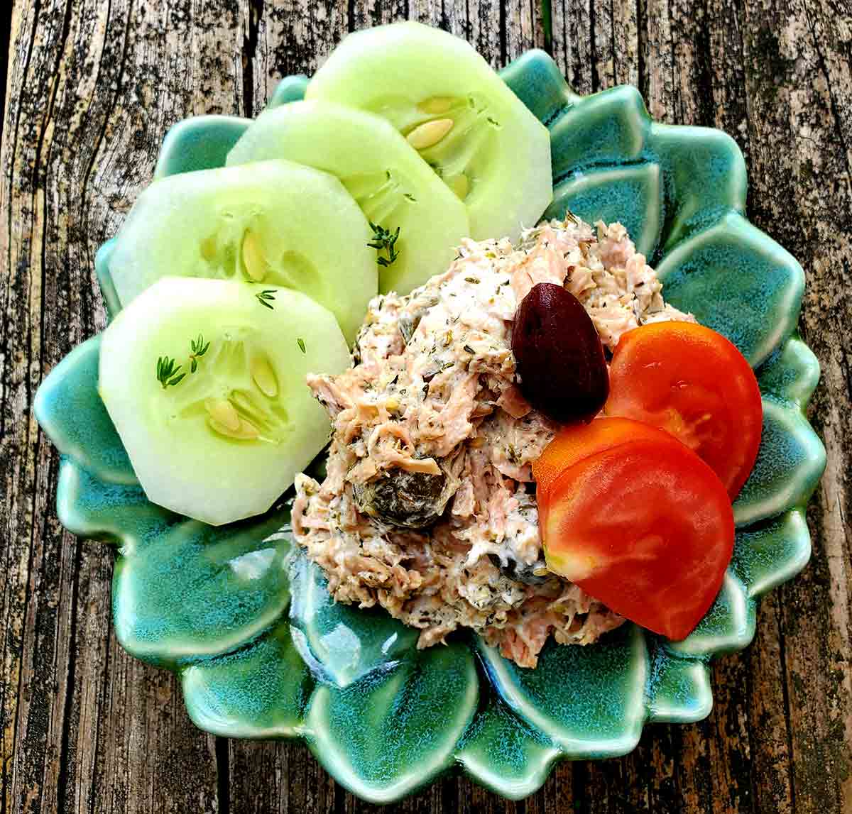 Tonfisksallad med kapris, yoghurt och Zaatar avbildad i en grön bladformad skål på ett träbord.