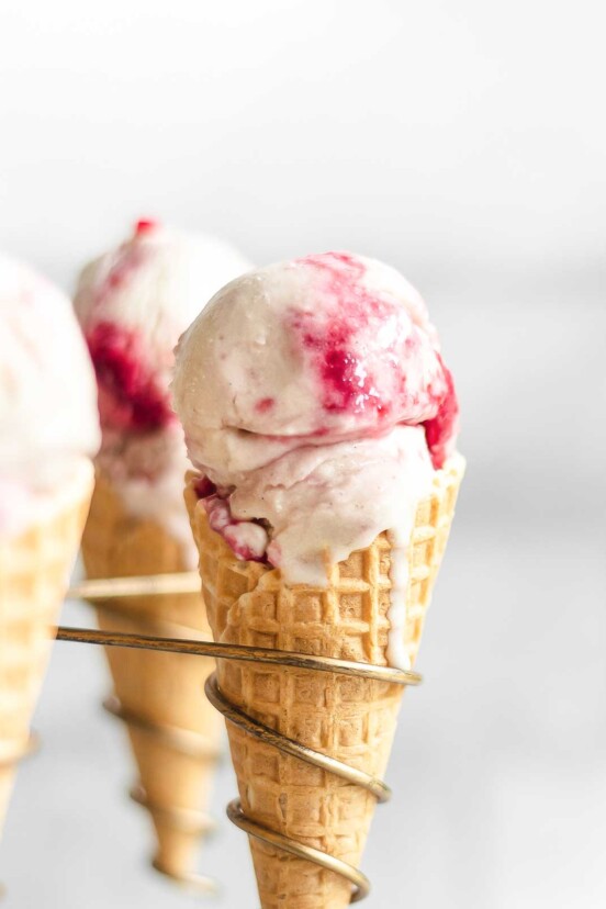 A close-up of 3 raspberry ripple ice cream in waffle cones.