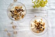 Three glass bowls filled with coffee mousse sprinkled with nuts, on a
