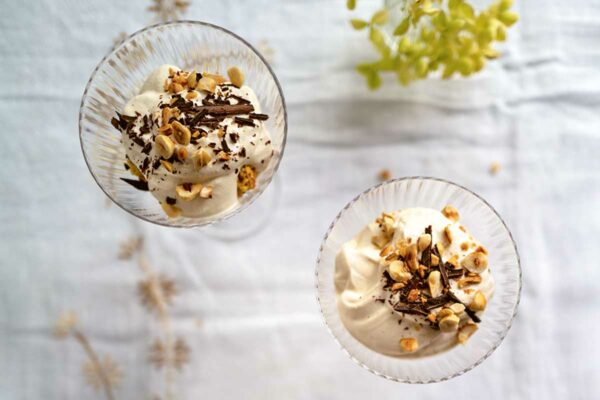 Three glass bowls filled with coffee mousse sprinkled with nuts, on a