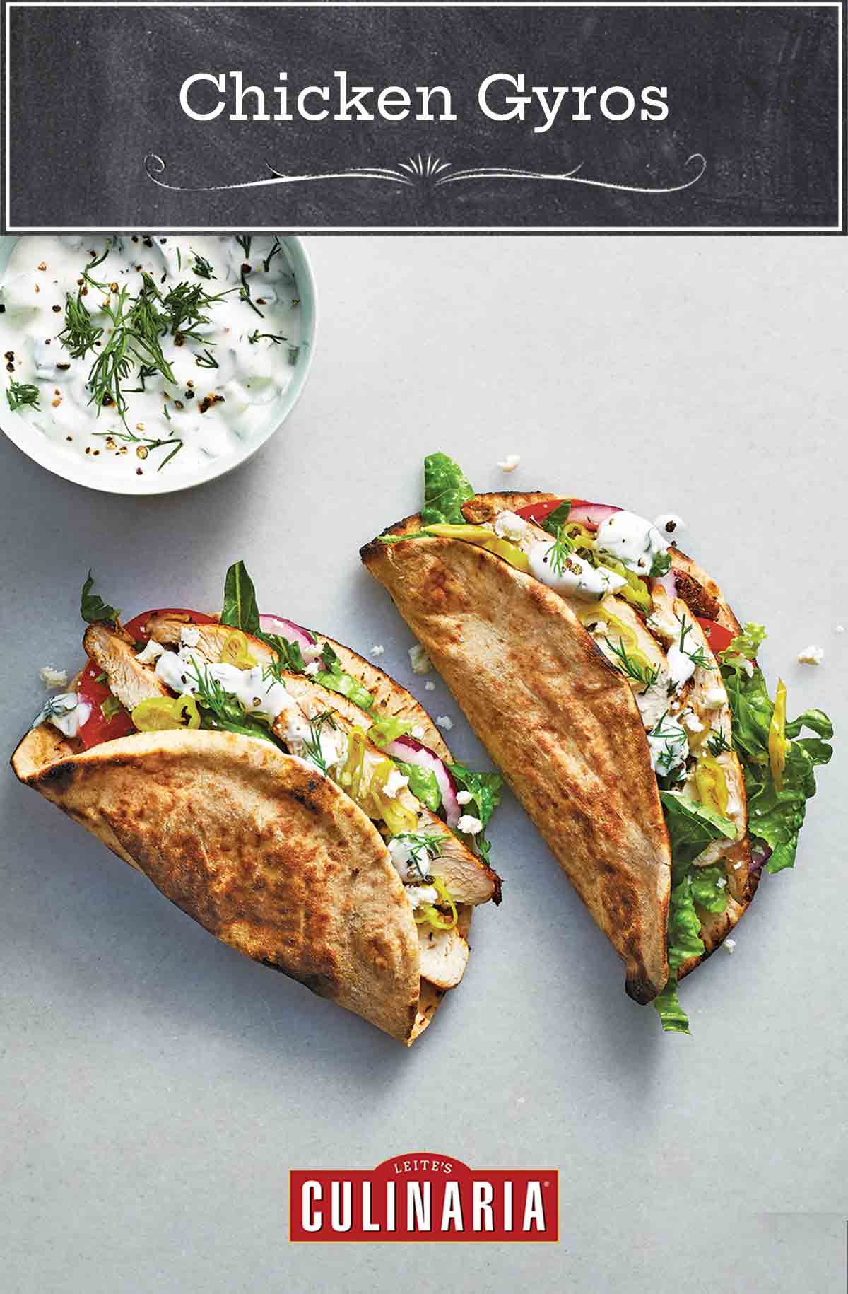 2 chicken gyros filled with romaine, chicken, tomatoes, red onion, pepperoncinis, and tzatziki, with a bowl of tzatziki next to it.