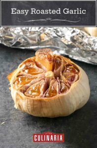 A bulb of roasted garlic with the top cut off, a sheet of aluminium foil in the background.