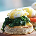 A cedar plank with 3 eggs Florentine, one with spinach, one with tomato, one with ham.