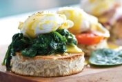 A cedar plank with 3 eggs Florentine, one with spinach, one with tomato, one with ham.