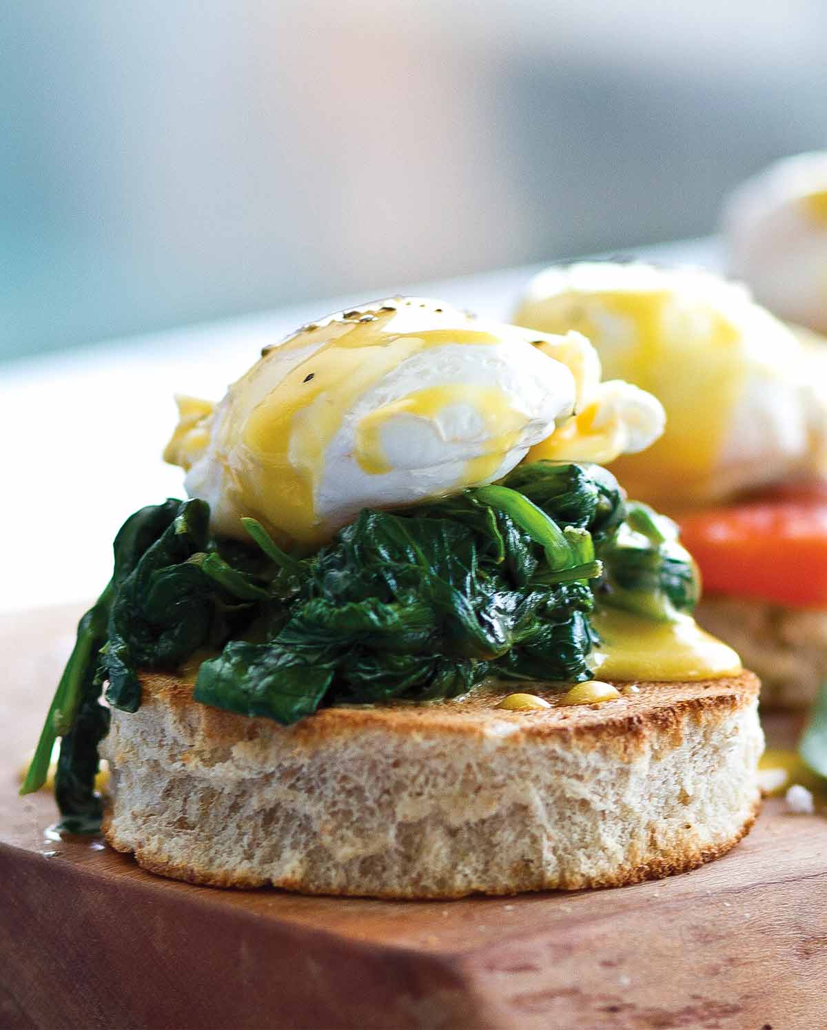 A cedar plank with 3 eggs Florentine, one with spinach, one with tomato, one with ham.