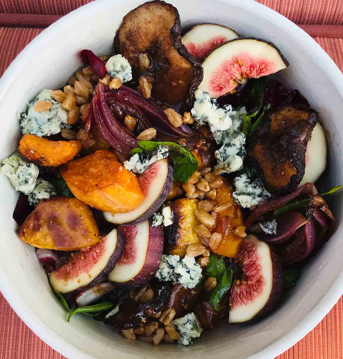 A white bowl filled with a mix of radicchio, blue cheese, squash, figs, parsley, and farro.