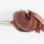 A silver spoon holding a large scoop of the milkiest chocolate ice cream in the world.