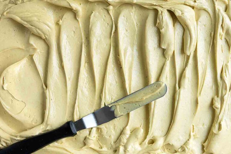 A large amount of pistachio buttercream frosting, swirled with a knife laying across it.