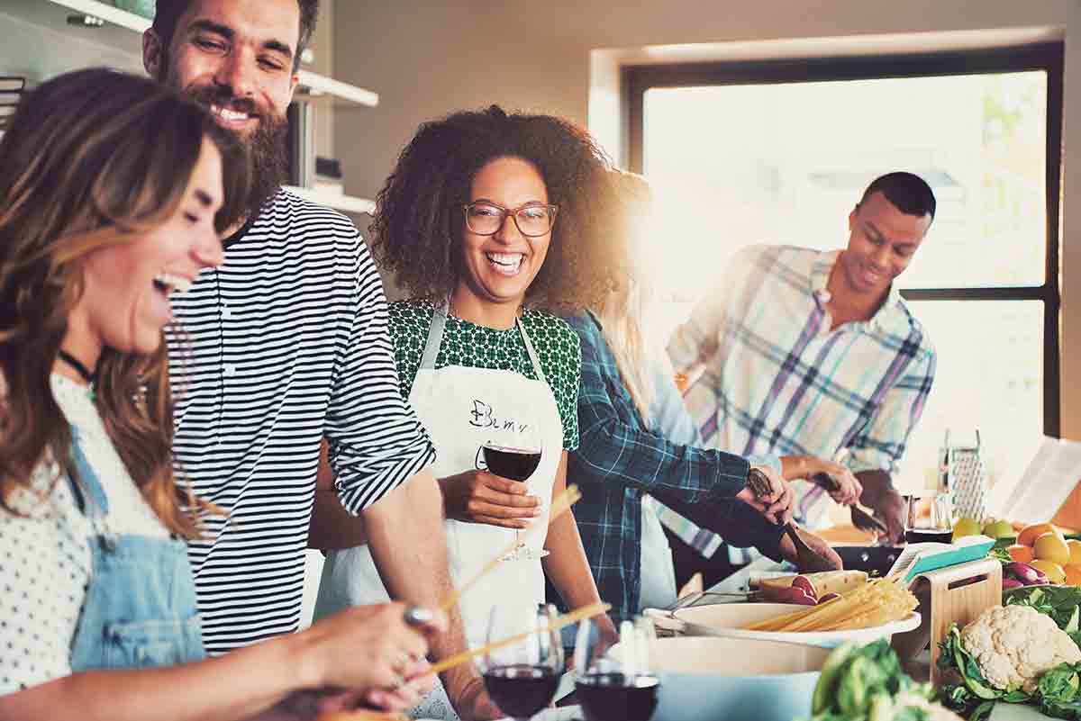 Photo of recipe testers gathered in kitchen laughing and cooking.