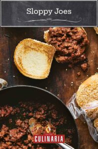A skillet filled with sloppy Joe meat mixture, flanked by a filled, untapped sandwich with a toasted top and a bag of sesame seed buns.