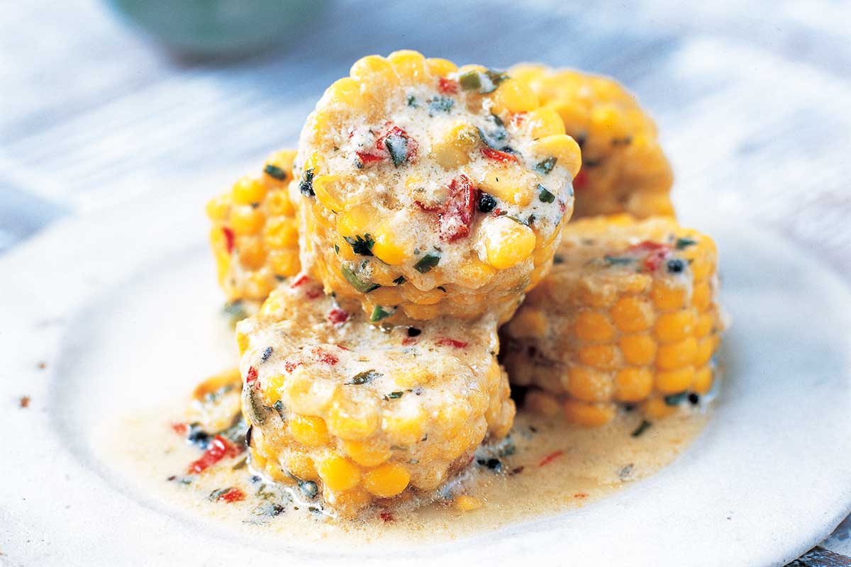 A white with 6 slices of corn on the cob, covered with coconut milk and a mixture of spices.