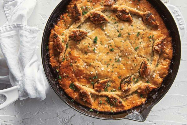 A beef bourguignon skillet pie in a cast-iron dish garnished with parsley and flaky sea salt.