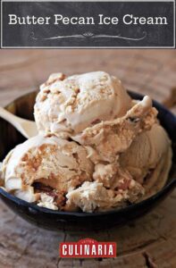 Butter pecan ice cream in a black bowl, with a spoon.