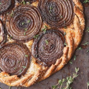 A caramelized onion and Gruyère galette with a rye crust and sprigs of thyme.