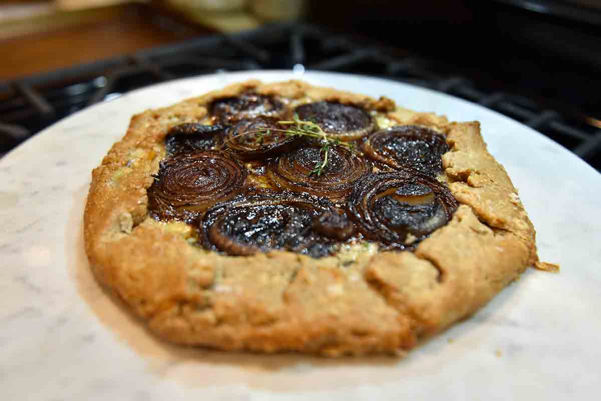 A caramelized onion and Gruyère galette with a rye crust and sprigs of thyme.