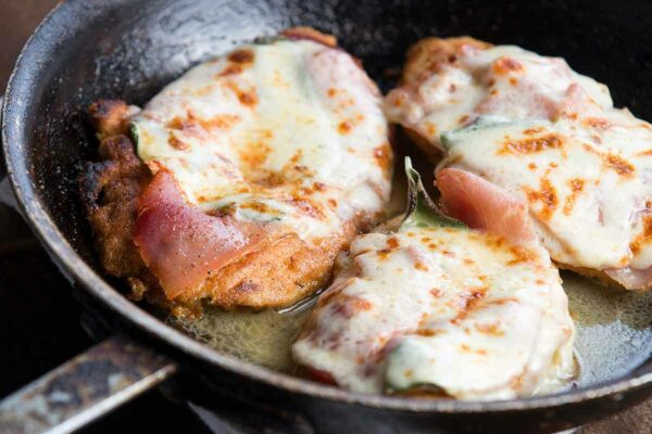 Chicken saltimbocca in a metal frying pan, sitting on a kitchen towel.