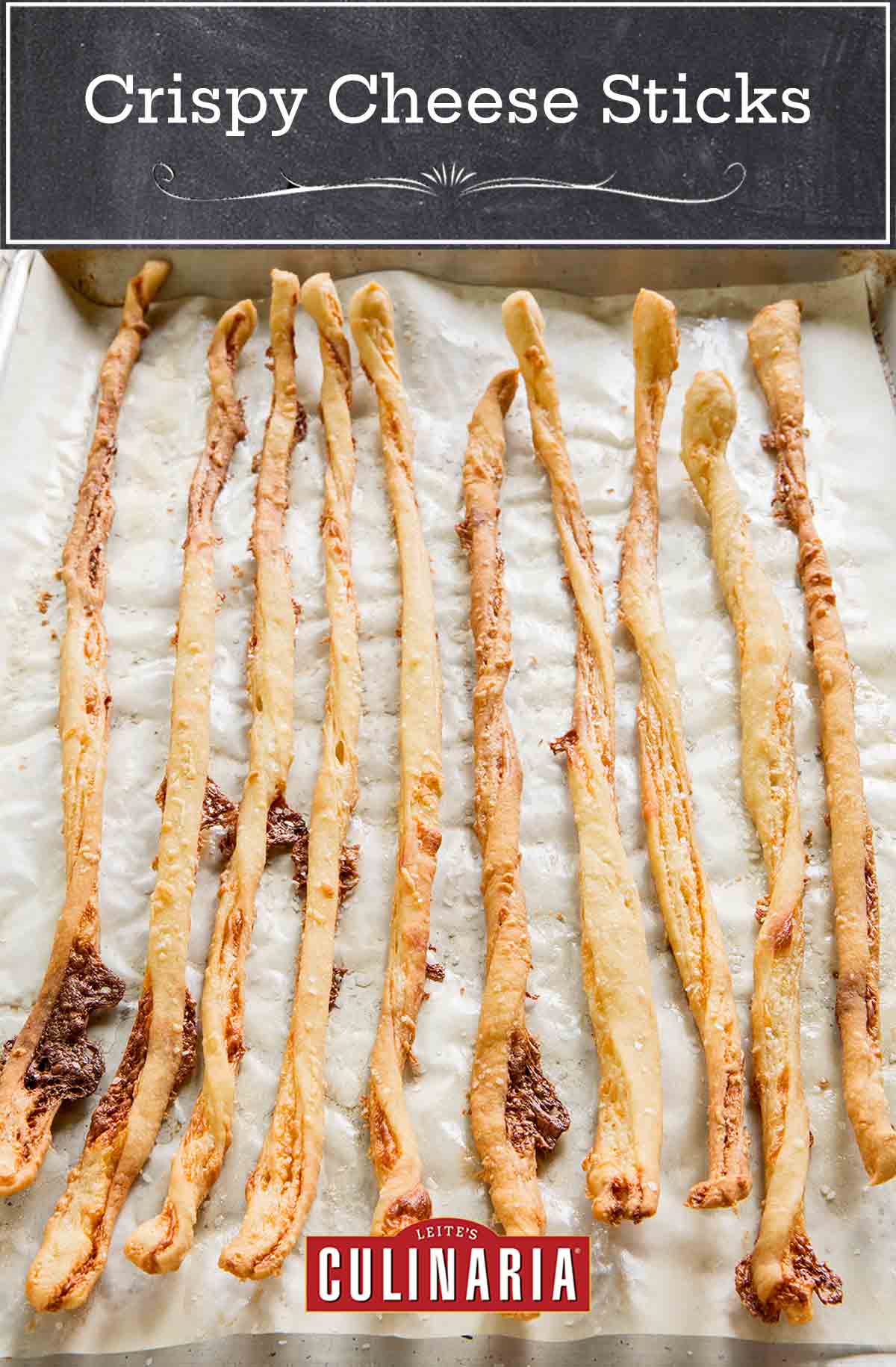 A baking sheet lined with parchment filled with 10 long, thin crispy cheese sticks.