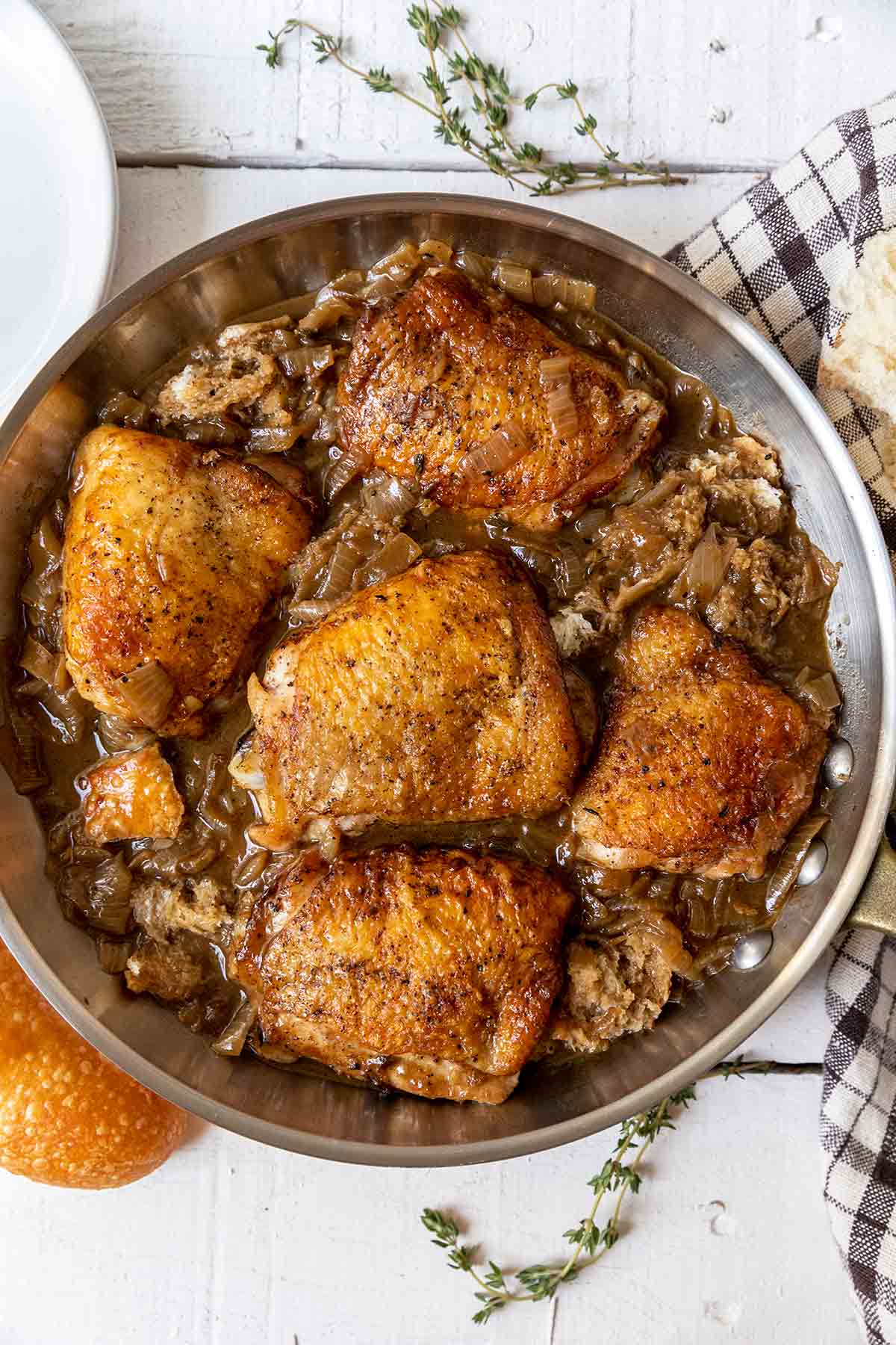 French onion skillet chicken with caramelized onions and chunks of bread tucked around the thighs