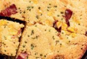 Dorie Greenspan's quick corn bread with bacon, corn, and green onions in a cast-iron skillet, and cut into squares.