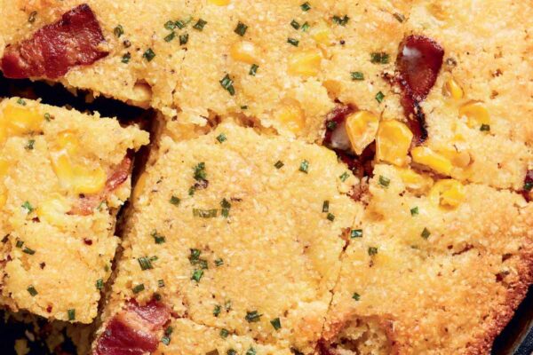Dorie Greenspan's quick corn bread with bacon, corn, and green onions in a cast-iron skillet, and cut into squares.