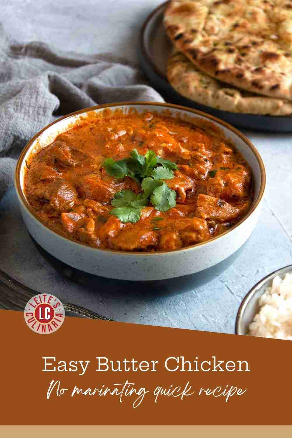 Tender chicken pieces simmered in a creamy orange curry sauce with fresh cilantro and melting butter in a gray bowl.