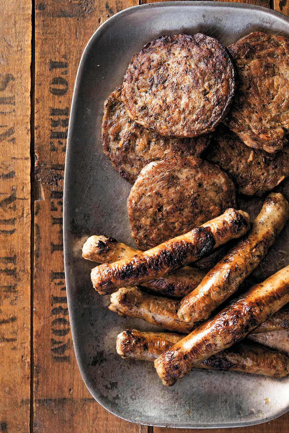 A metal platter with 4 round homemade breakfast sausage and 6 link sausages.