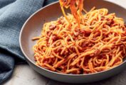A pottery bowl filled with Instant Pot spaghetti with meat sauce, with a forkful of pasta.