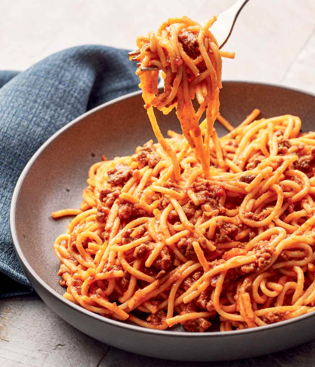 En keramikskål fylld med Instant Pot-spaghetti med köttsås, med en gaffel pasta.