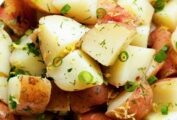 A white bowl filled with potato salad with dill, including quartered red-skinned potatoes, tossed with dill, scallions, and lemon zest.
