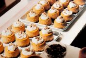 Pumpkin cheesecakes with gingersnap pecan crust on 2 sheet pans, topped with whipped cream and nuts.