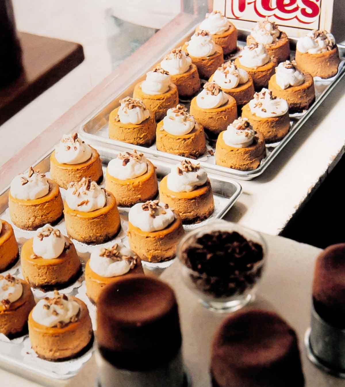 Pumpkin cheesecakes with gingersnap pecan crust on 2 sheet pans, topped with whipped cream and nuts.