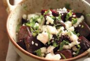 Roasted beet, feta, and mint salad in a pottery bowl on a. linen napkin.