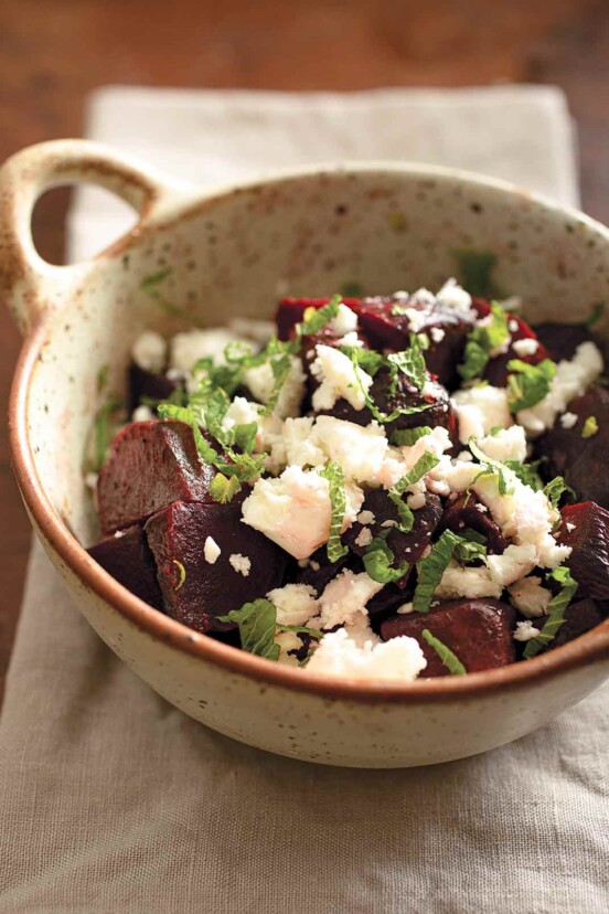 Roasted beet, feta, and mint salad in a pottery bowl on a. linen napkin.