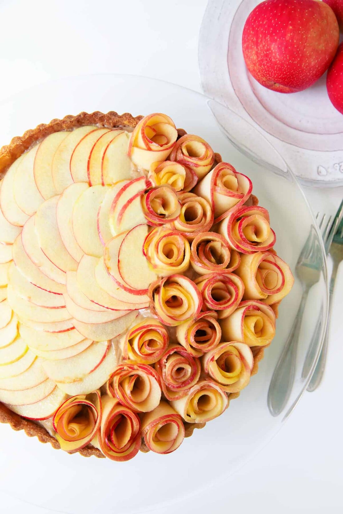 An apple rose tart on a glass cake stand.