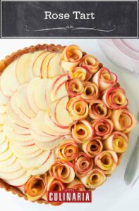 An apple rose tart on a glass cake stand.