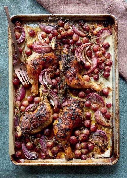 Sheet pan chicken with rosemary and grapes on a large metal pan with a fork, on a linen napkin.