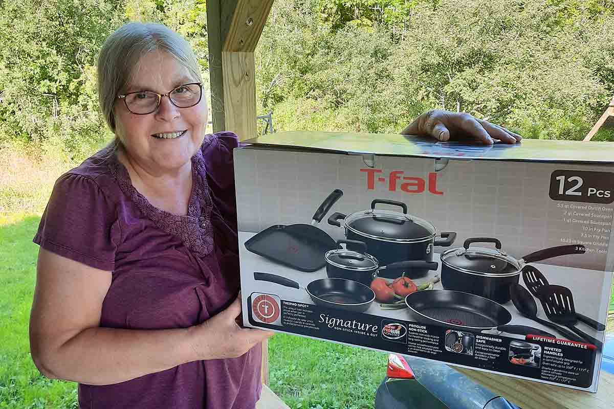 An very happy LC giveaway winner holding a T-Fal pots and pans set still in its box.
