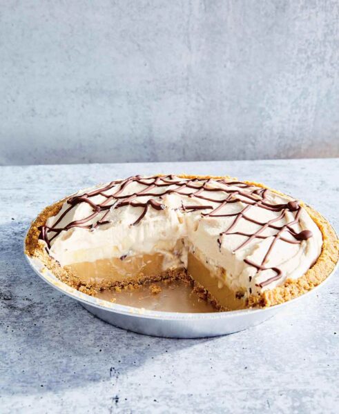 Banoffee pie in a metal pie plate with a quarter of the pie missing.