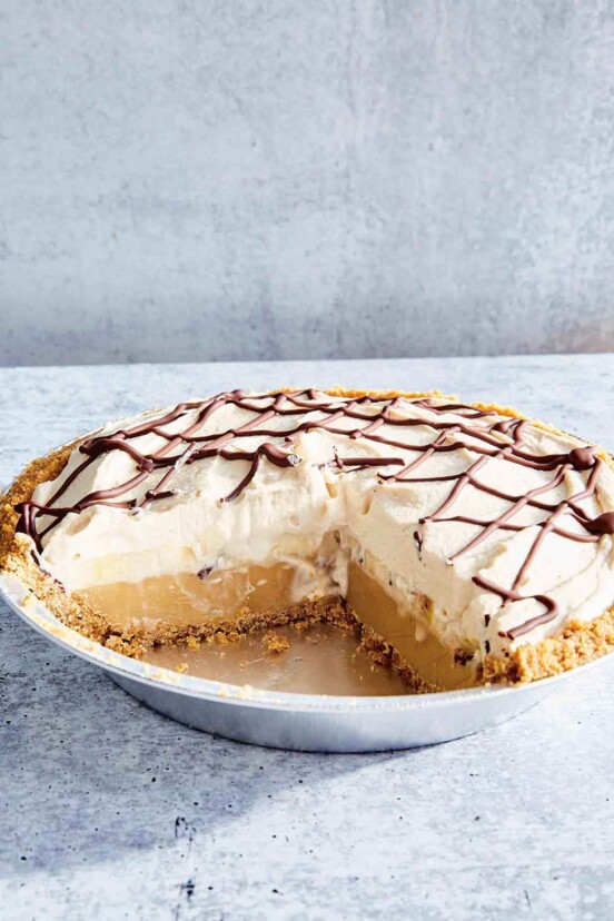 Banoffee pie in a metal pie plate with a quarter of the pie missing.