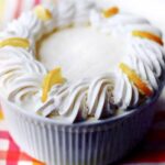 Barefoot Contessa fresh lemon mousse in a soufflé dish with the edges decorated with swirls of whipped cream and lemon slices.