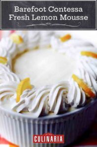 Barefoot Contessa fresh lemon mousse in a soufflé dish with the edges decorated with swirls of whipped cream and lemon slices.